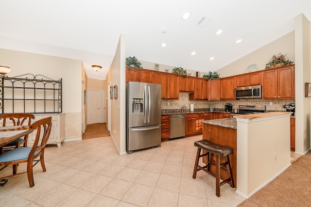 kitchen featuring lofted ceiling, light tile patterned flooring, tasteful backsplash, and stainless steel appliances