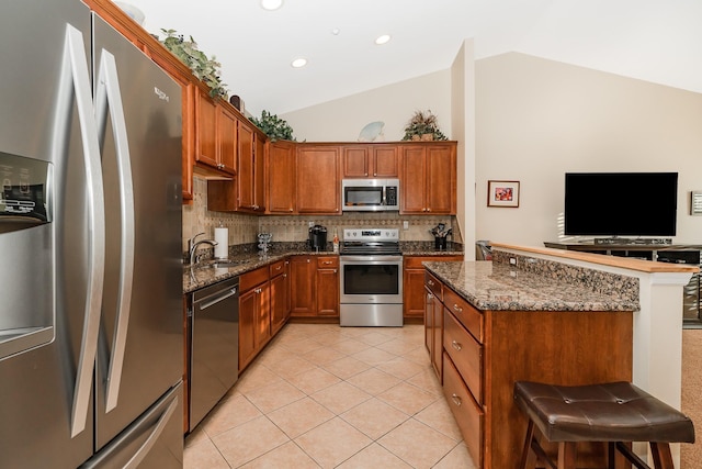 kitchen with light tile patterned floors, brown cabinetry, appliances with stainless steel finishes, and a sink