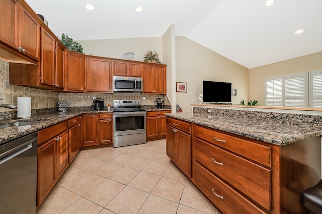 kitchen featuring a sink, tasteful backsplash, appliances with stainless steel finishes, light tile patterned flooring, and lofted ceiling