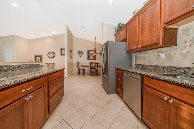 kitchen with backsplash, vaulted ceiling, light tile patterned floors, dark stone countertops, and stainless steel appliances