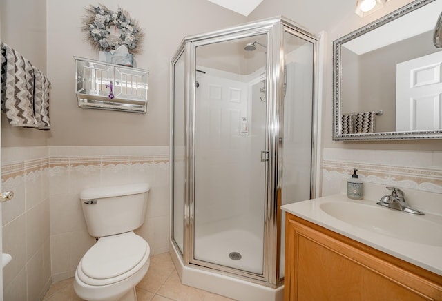 full bath featuring vanity, a shower stall, wainscoting, tile walls, and tile patterned floors