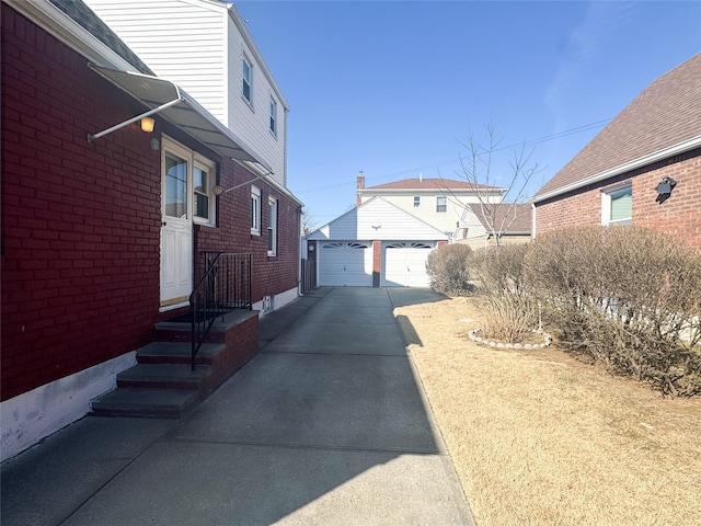 view of home's exterior with a garage, brick siding, and an outdoor structure