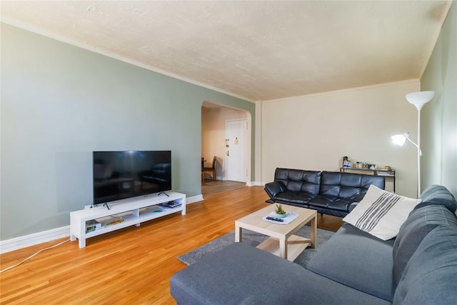 living room with arched walkways, crown molding, wood finished floors, and baseboards