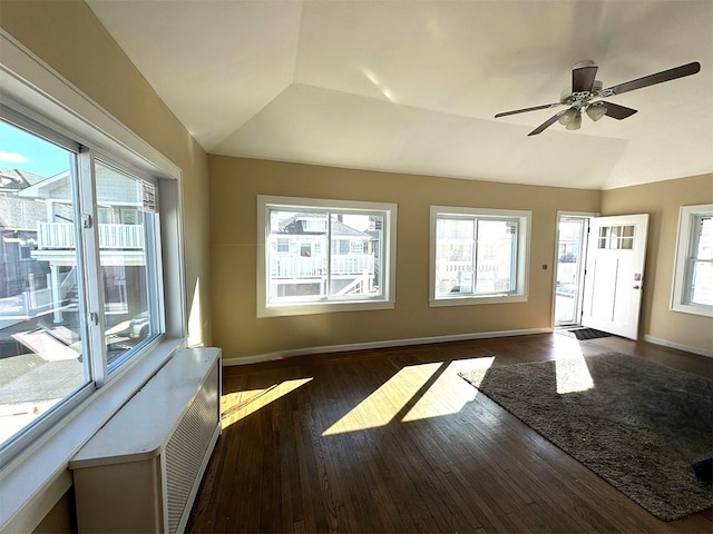 interior space featuring baseboards, wood-type flooring, a healthy amount of sunlight, and vaulted ceiling