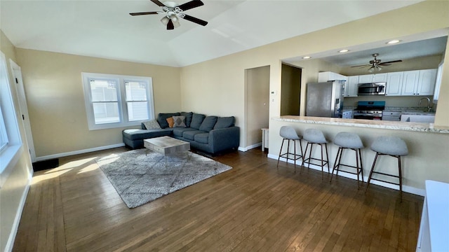 living area with dark wood finished floors, lofted ceiling, baseboards, and ceiling fan