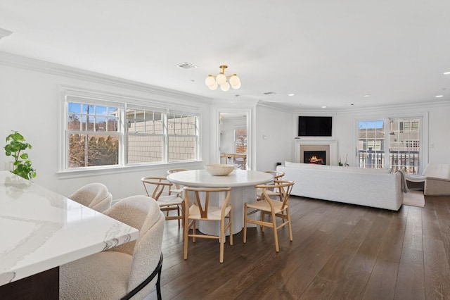 dining area with visible vents, dark wood finished floors, a lit fireplace, crown molding, and recessed lighting