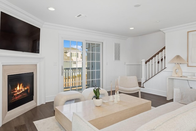 living room with visible vents, a premium fireplace, ornamental molding, and wood finished floors