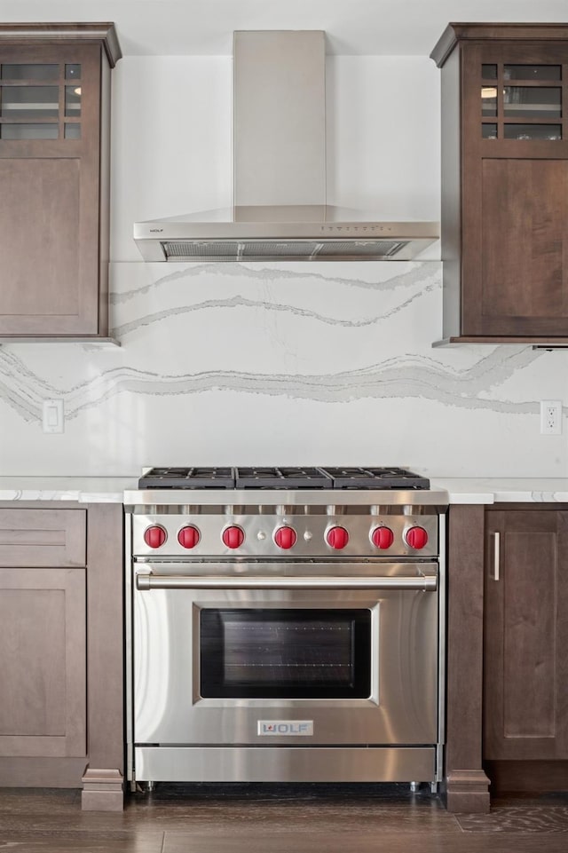 kitchen with light countertops, premium stove, wall chimney range hood, and decorative backsplash