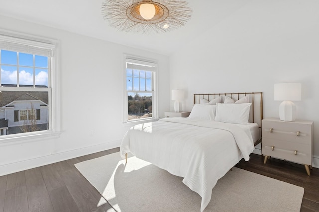 bedroom featuring dark wood-style floors, lofted ceiling, and baseboards