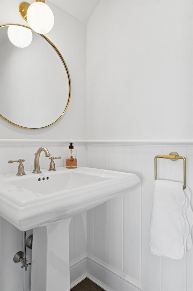 bathroom featuring a wainscoted wall, a decorative wall, and a sink