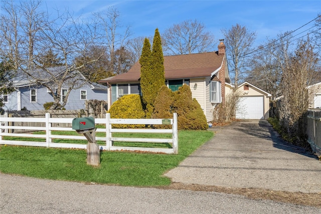 bungalow-style home with a garage, a fenced front yard, a chimney, an outdoor structure, and a front yard