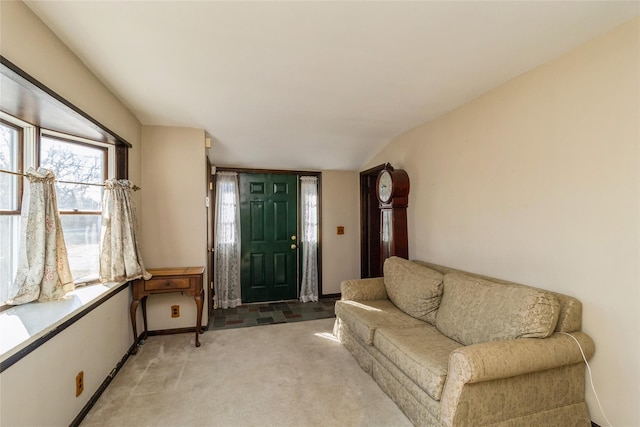 foyer entrance featuring lofted ceiling, light colored carpet, and baseboards