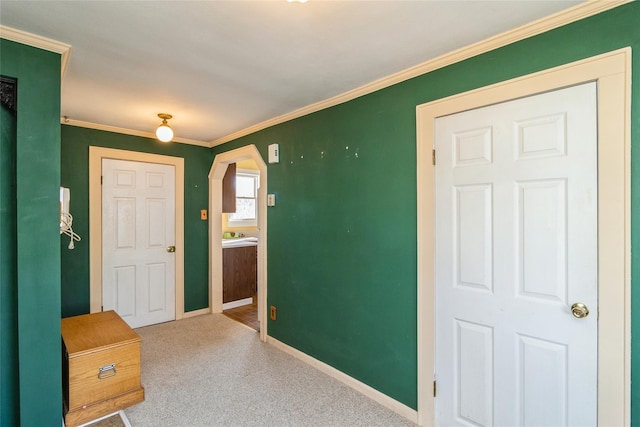 carpeted foyer entrance with ornamental molding, arched walkways, and baseboards