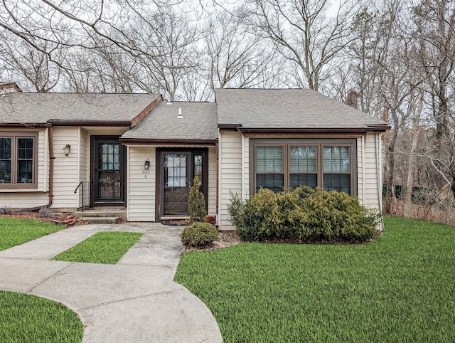 ranch-style home featuring a shingled roof, a front yard, and a chimney