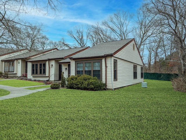 view of front of home with roof with shingles and a front yard