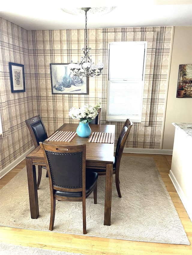 dining area featuring a notable chandelier, wood finished floors, and baseboards