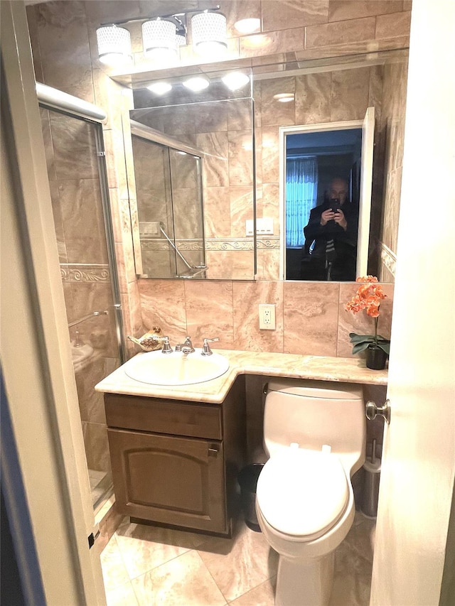 bathroom with a stall shower, tile walls, toilet, vanity, and backsplash