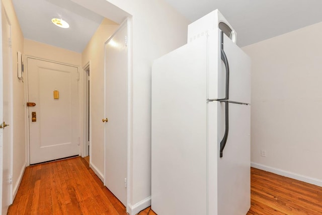 corridor with baseboards and light wood-style floors