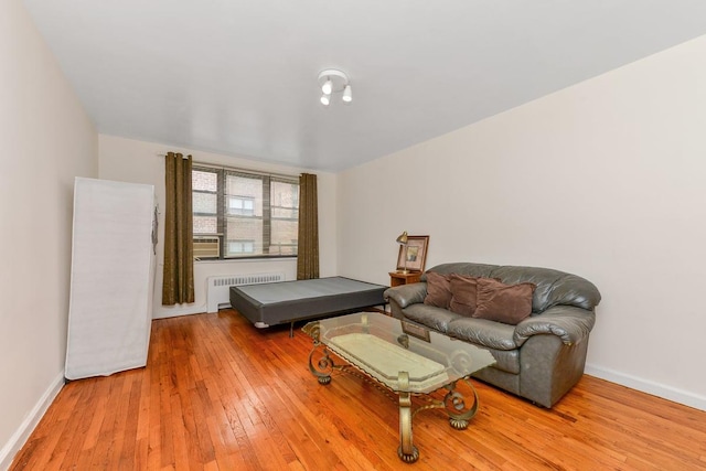 bedroom featuring hardwood / wood-style floors, radiator heating unit, and baseboards