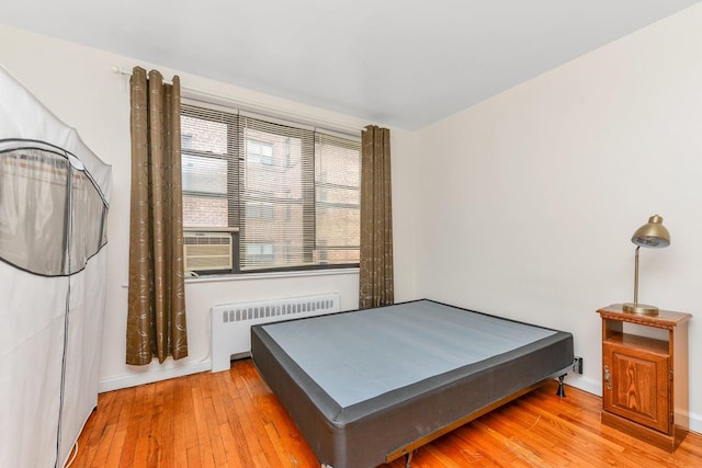 bedroom with radiator and hardwood / wood-style flooring