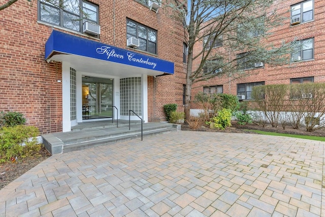 doorway to property featuring brick siding and cooling unit