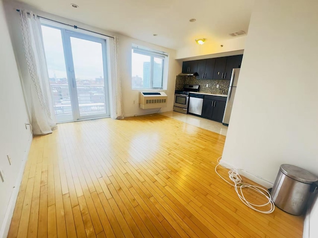 kitchen featuring visible vents, appliances with stainless steel finishes, dark cabinets, light wood-style floors, and backsplash