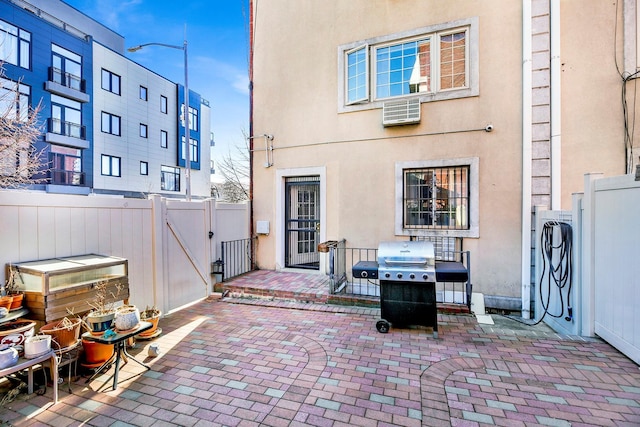 rear view of property with a gate, a patio area, fence, and stucco siding