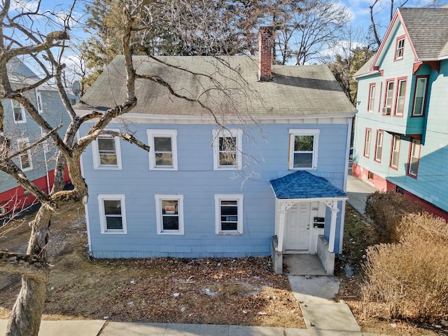 view of front of home with a chimney and roof with shingles