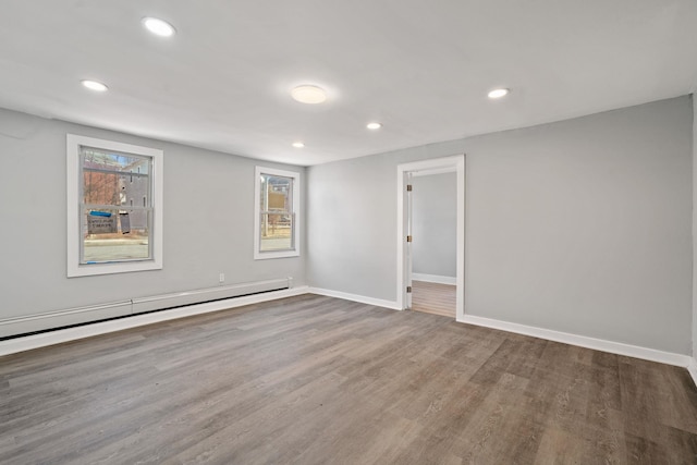 spare room with a baseboard radiator, baseboards, wood finished floors, and recessed lighting