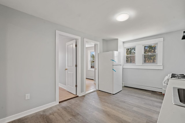 kitchen featuring a baseboard heating unit, light wood-type flooring, freestanding refrigerator, and baseboards