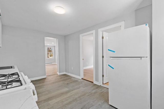 kitchen with light wood-style floors, white appliances, baseboards, and light stone countertops