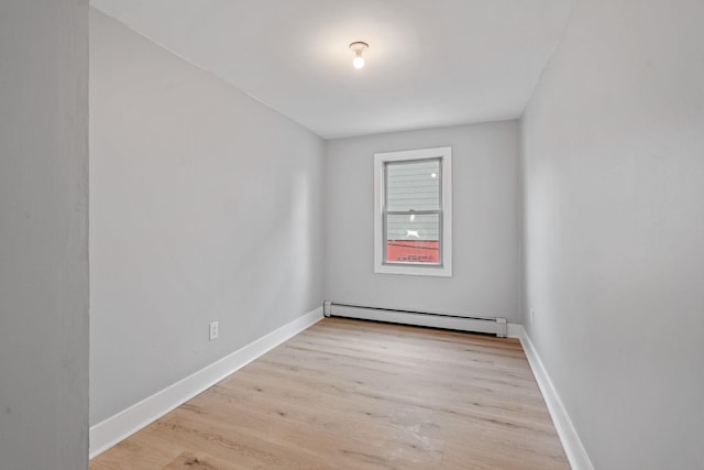 unfurnished room featuring a baseboard radiator, baseboards, and wood finished floors