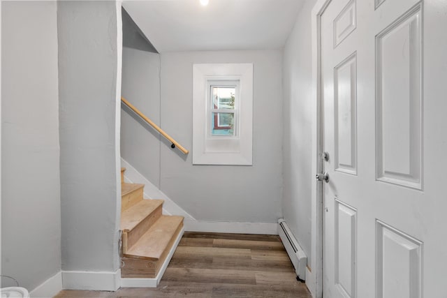 doorway to outside with stairway, a baseboard radiator, wood finished floors, and baseboards