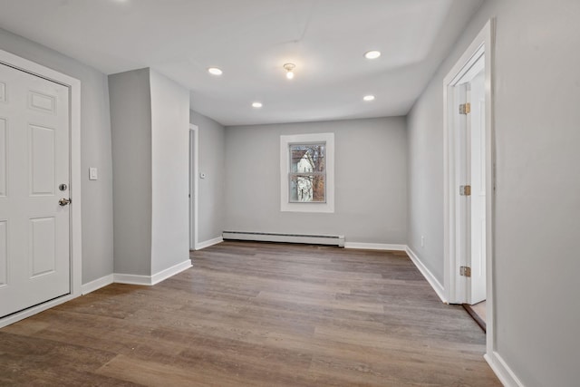 spare room featuring recessed lighting, a baseboard radiator, wood finished floors, and baseboards