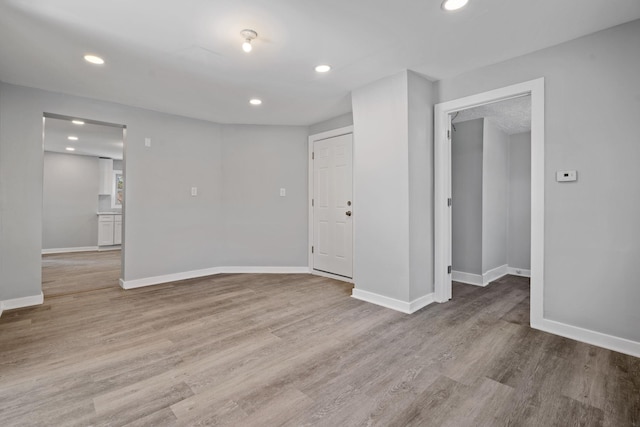 unfurnished room with baseboards, wood finished floors, and recessed lighting