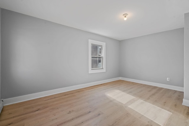 spare room with baseboards, baseboard heating, and wood finished floors