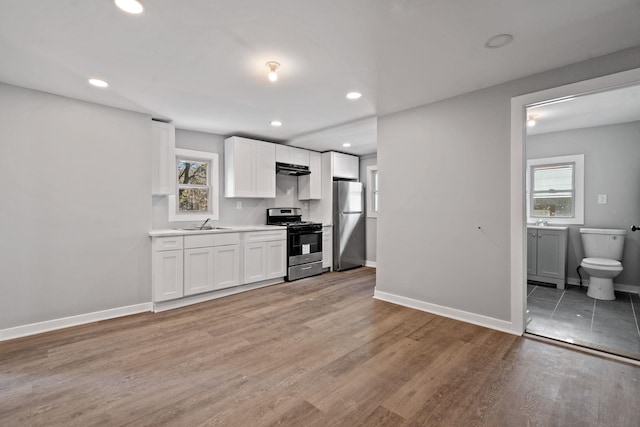 kitchen featuring recessed lighting, light wood-style flooring, appliances with stainless steel finishes, white cabinetry, and baseboards
