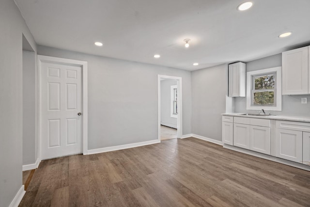 interior space featuring recessed lighting, baseboards, a sink, and wood finished floors