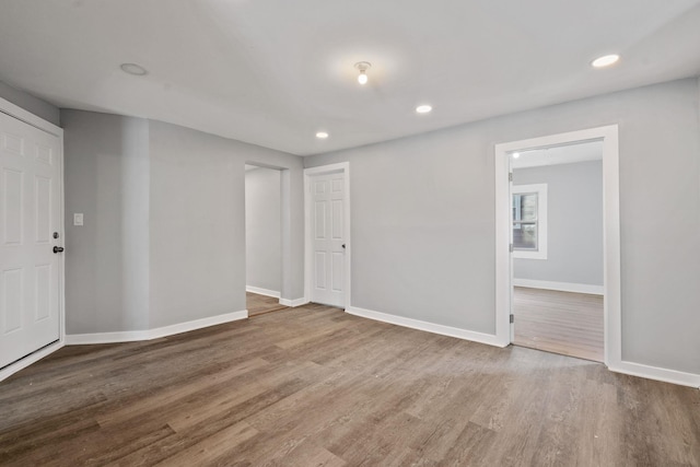 unfurnished room featuring baseboards, wood finished floors, and recessed lighting