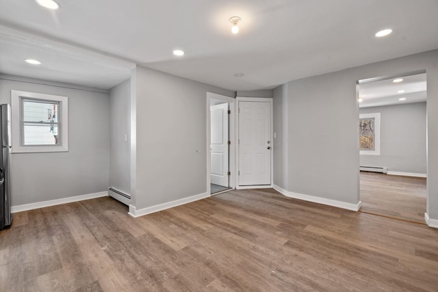 below grade area with a baseboard radiator, recessed lighting, baseboards, and wood finished floors