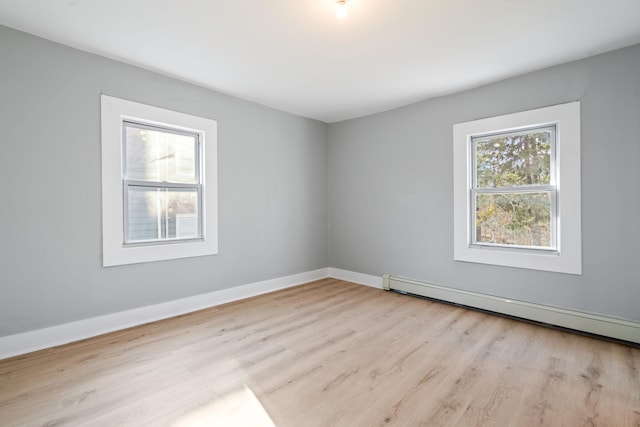 unfurnished room with baseboards, a baseboard heating unit, and wood finished floors