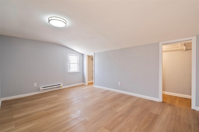 interior space with baseboards, vaulted ceiling, a baseboard radiator, and light wood-style floors