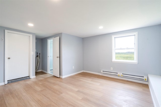 empty room featuring light wood finished floors, baseboards, baseboard heating, and recessed lighting