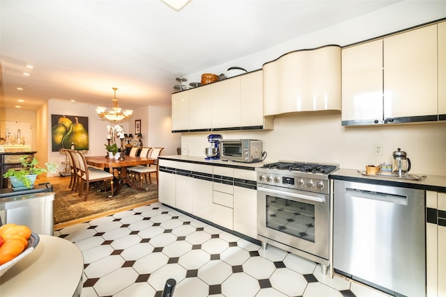 kitchen with wall chimney range hood, a chandelier, a toaster, light floors, and stainless steel appliances