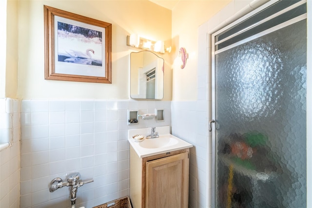 full bath with vanity, tile walls, a stall shower, and wainscoting