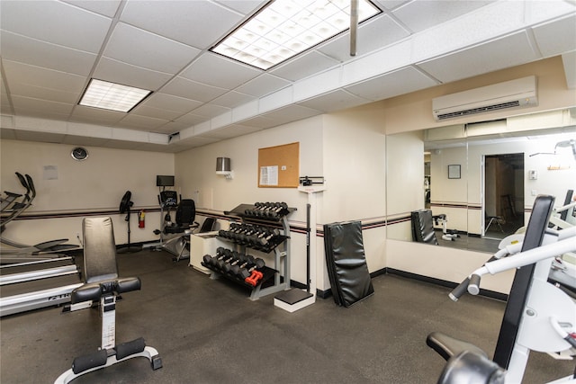 gym with a drop ceiling, baseboards, and a wall unit AC