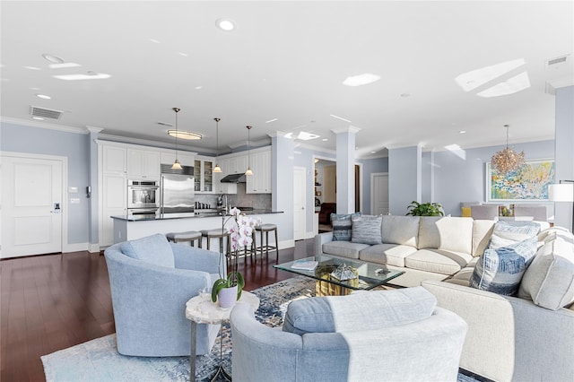 living room featuring visible vents, dark wood finished floors, crown molding, and ornate columns