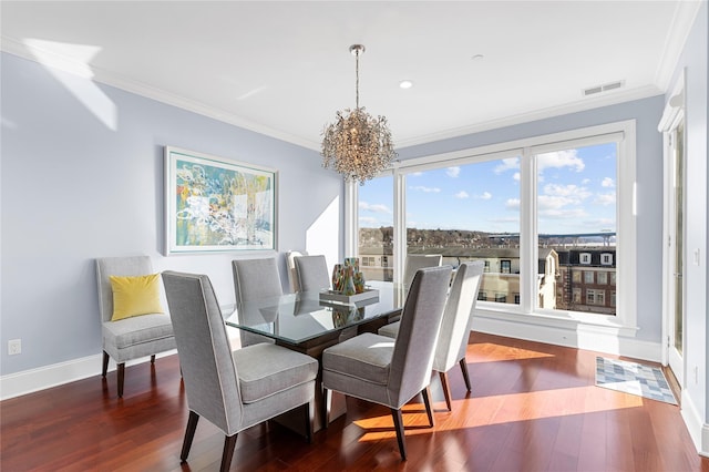 dining space featuring wood finished floors, baseboards, visible vents, ornamental molding, and a notable chandelier