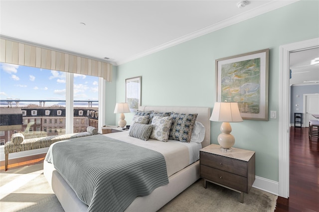 bedroom featuring baseboards, wood finished floors, and crown molding