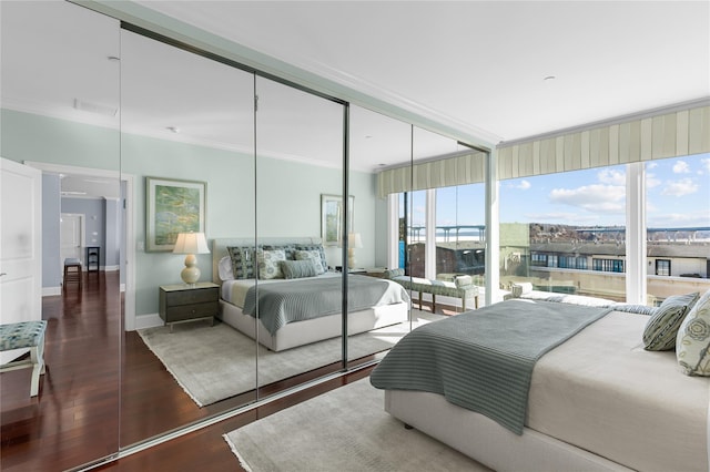 bedroom with visible vents, wood finished floors, a closet, crown molding, and baseboards